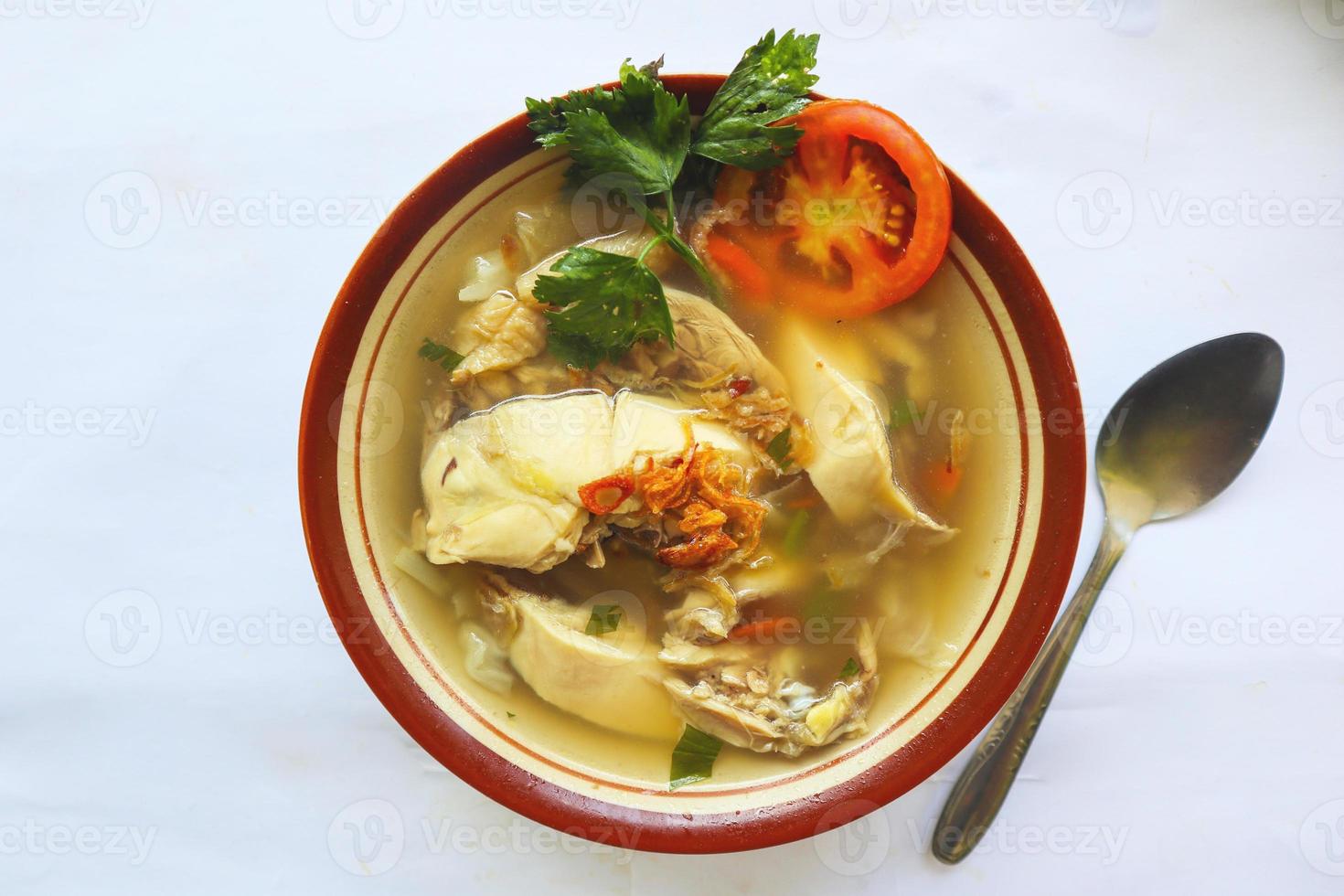 Chicken soup served with vegetables, tomatoes, celery in a bowl, spoon and fork. with black background photo