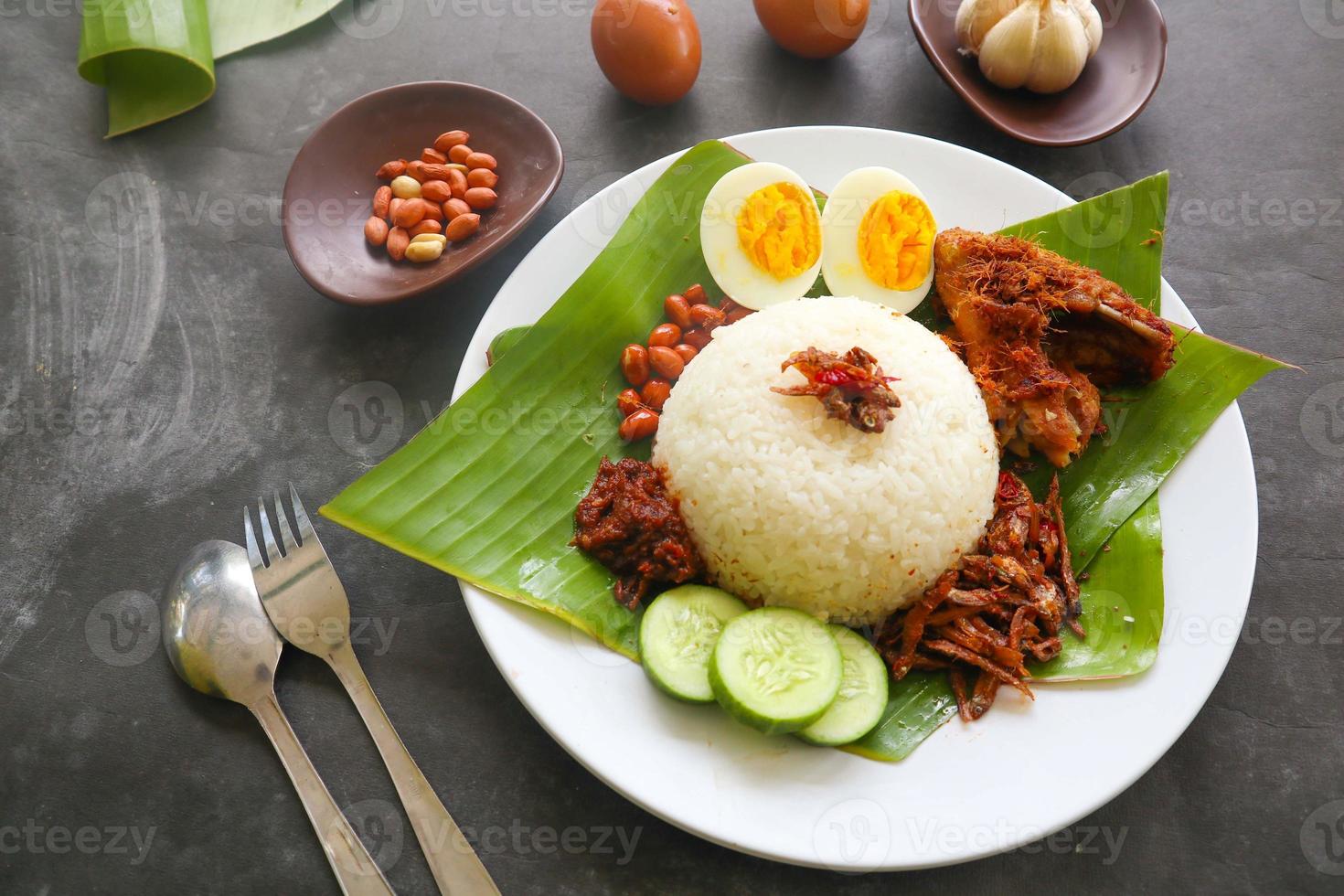 nasi lemak, is traditional malay made boiled eggs, beans, anchovies, chili sauce, cucumber. from dish served on a banana leaf photo