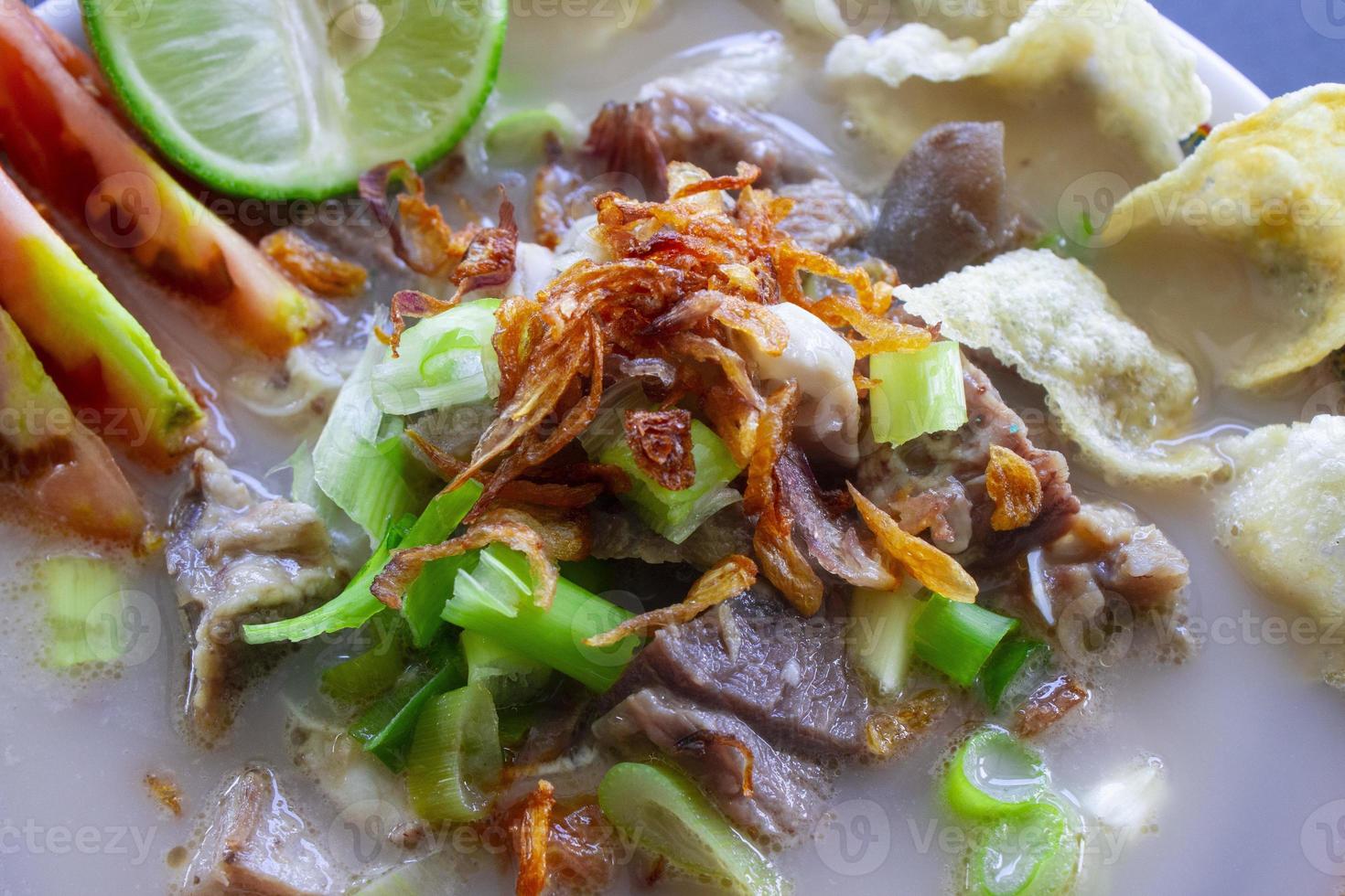 sop kaki kambing a traditional food from Betawi, Jakarta Indonesia, made from mutton or lamb, offal, spices. isolated on black background.This food is like lamb stew on black background photo