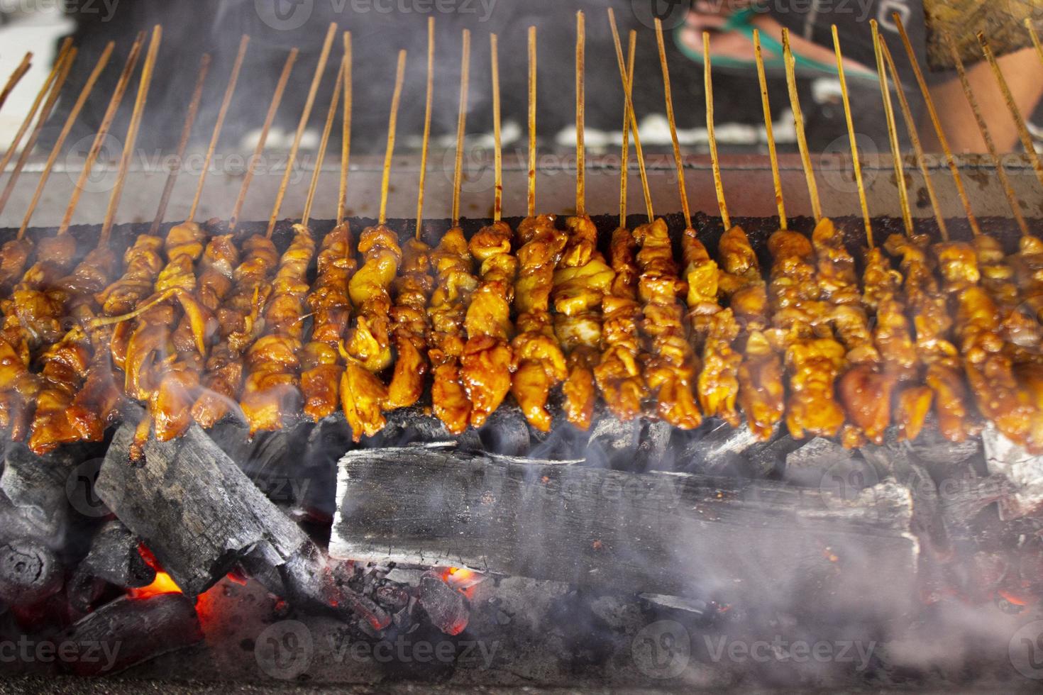 sate ayam or chicken satay with rice cake lontong served with peanut sauce, sliced chilis and shallot. photo with seletive focus