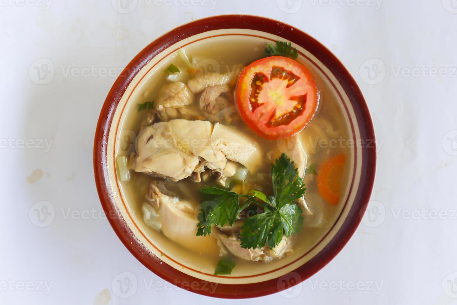 Chicken soup served with vegetables, tomatoes, celery in a bowl, spoon and fork. with black background photo