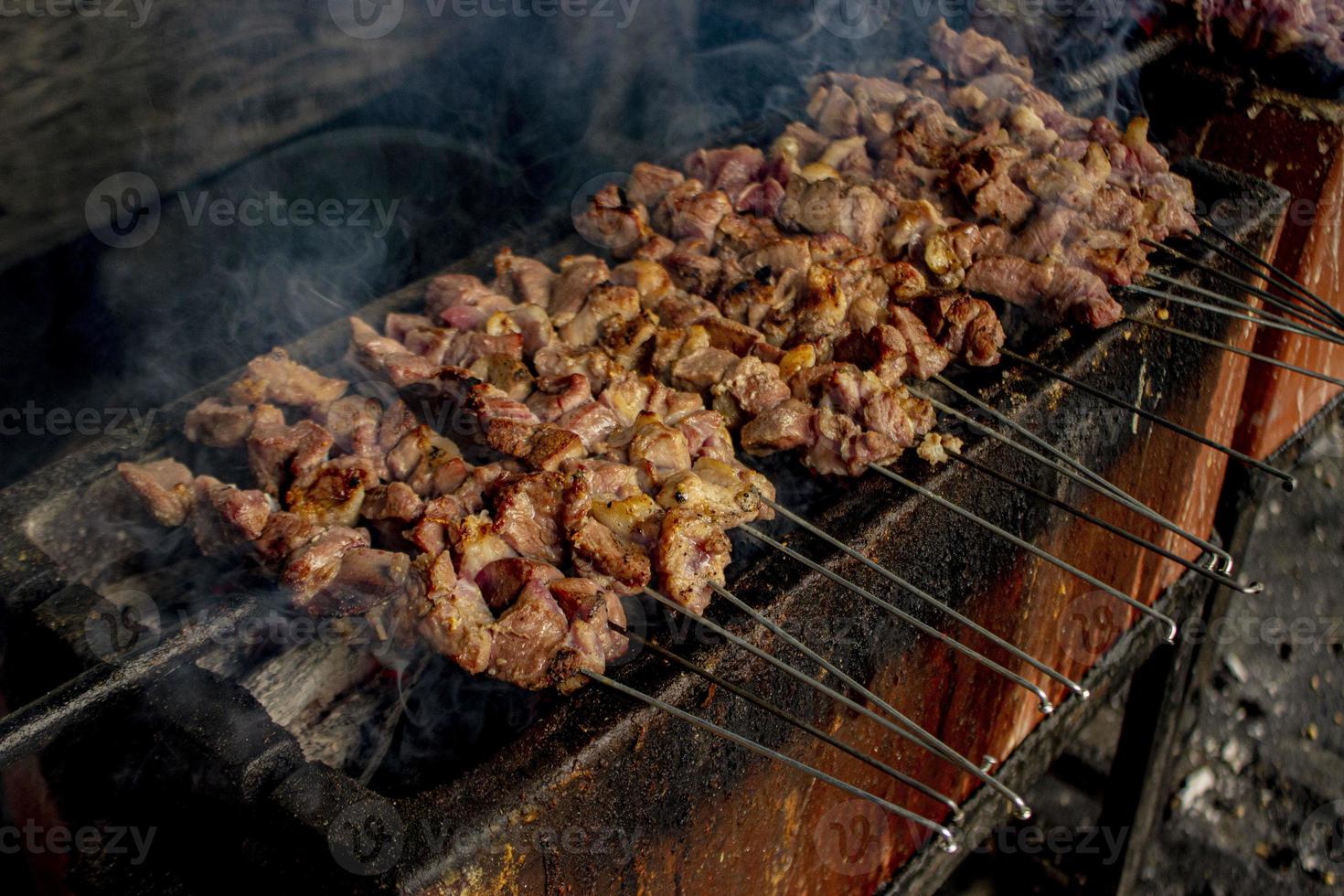 sate klatak o sate kambing o satay de cabra, cordero, cordero o carne de cabra satay con ingrediente de carbón en fuego rojo asado por personas, indonesia cocinando satay. con enfoque selectivo foto