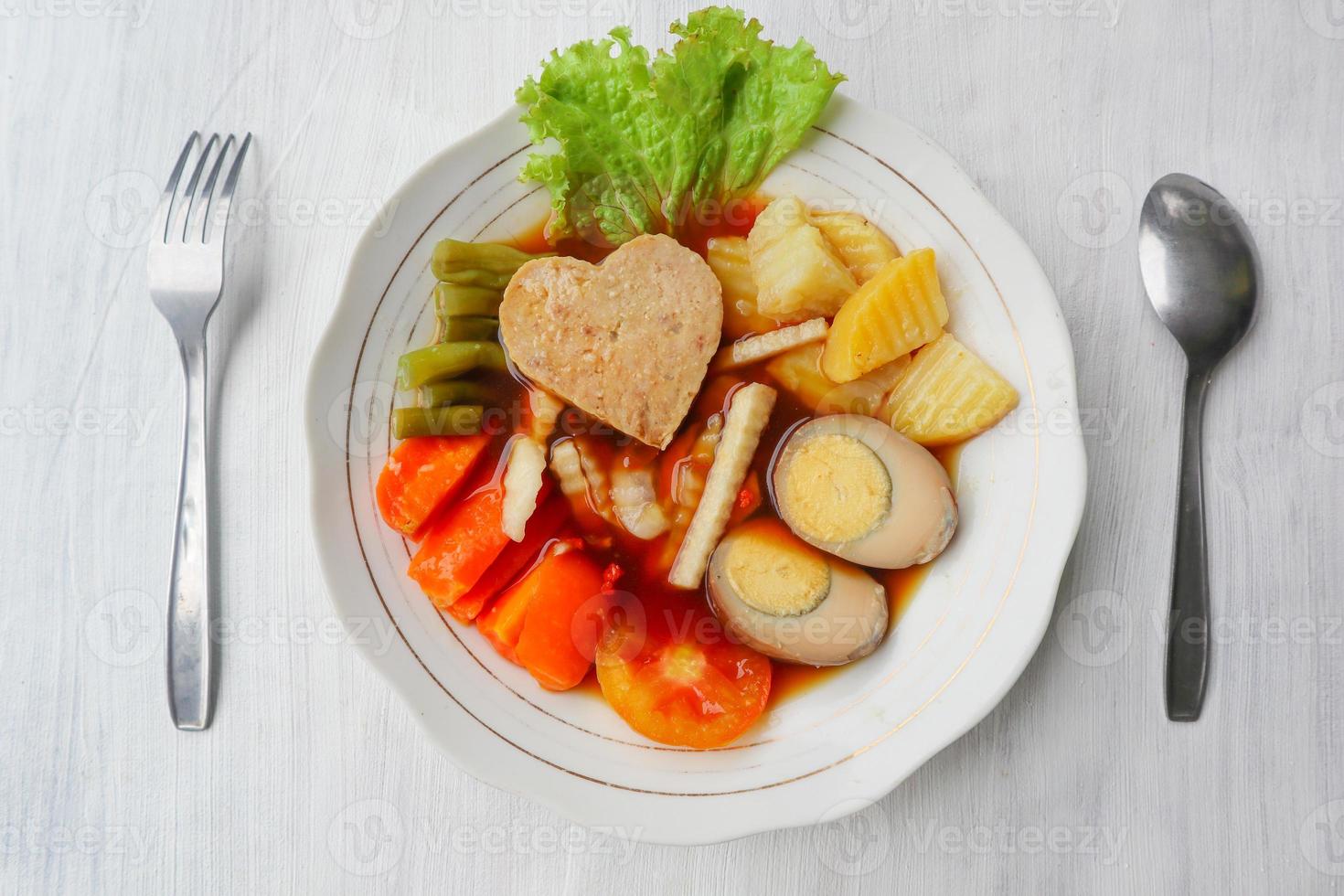 selat solo is traditional salad food from indonesia. made from hard-boiled eggs, boiled chickpeas, boiled carrots, hash browns and lettuce, steak or bistik. served on wood table photo