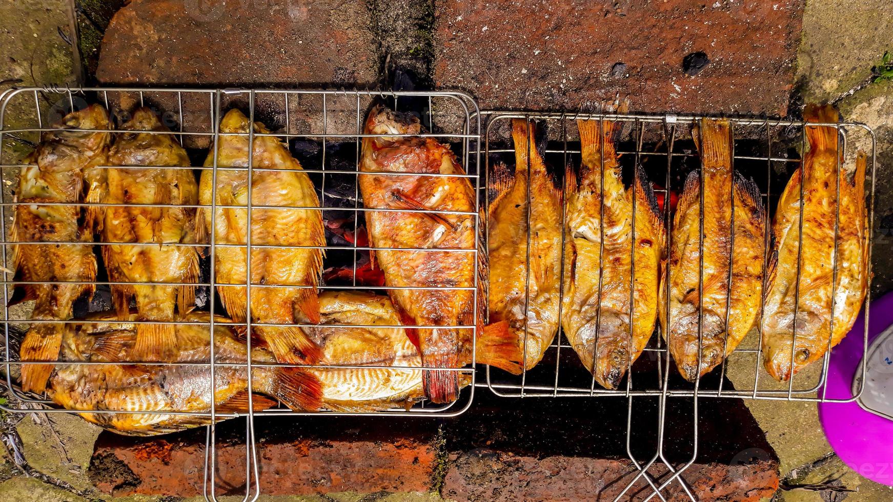 pescado a la parrilla, pescado a la parrilla tilapia del nilo a la parrilla sobre carbón caliente foto