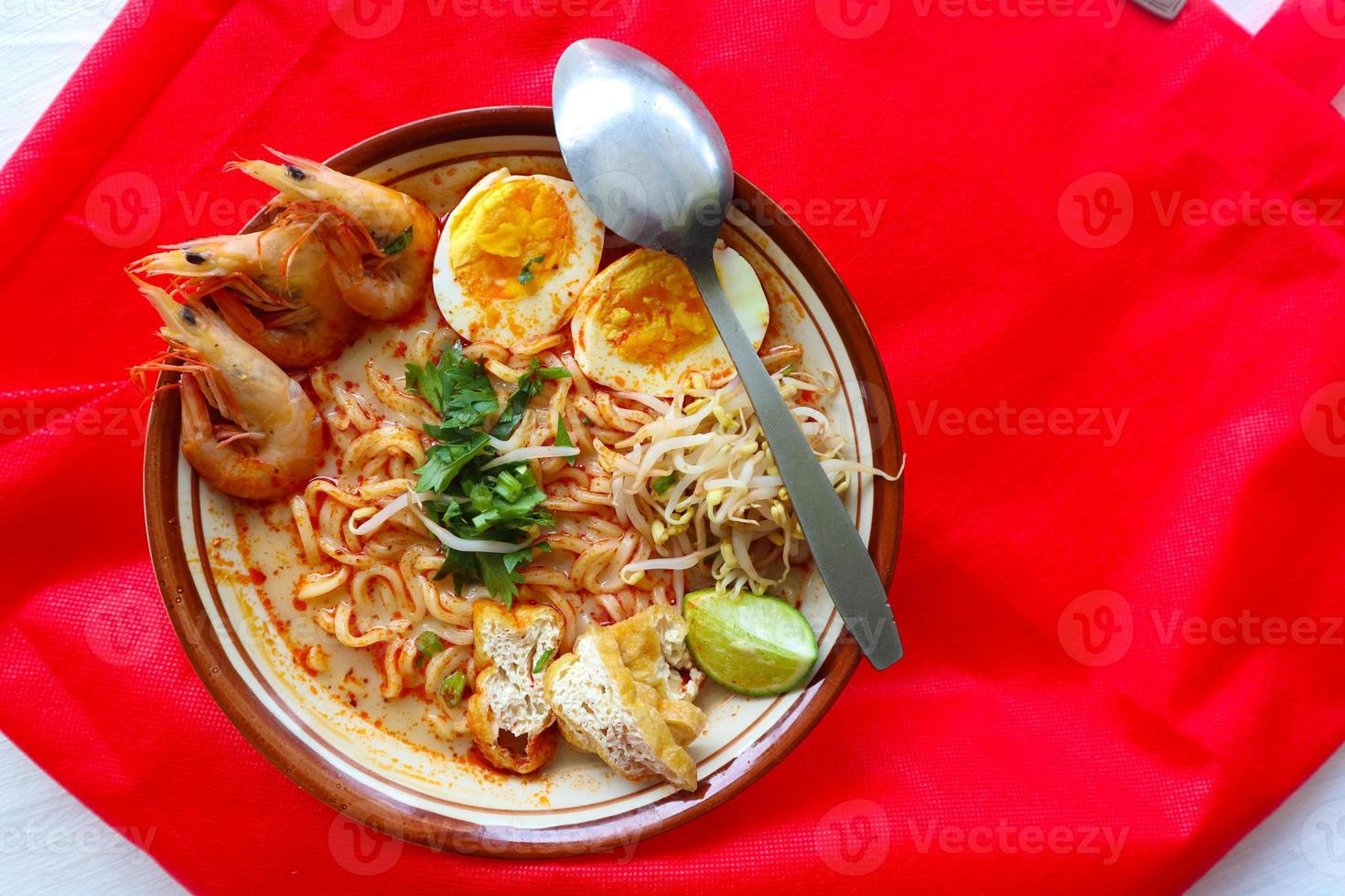 laksa, laksa curry made from vermicelli, noodles, bean sprouts, egg, tofu lime, and shrimp with a spicy soup sauce that is rich in spices. laksa served on bowl, isolated on white background. photo