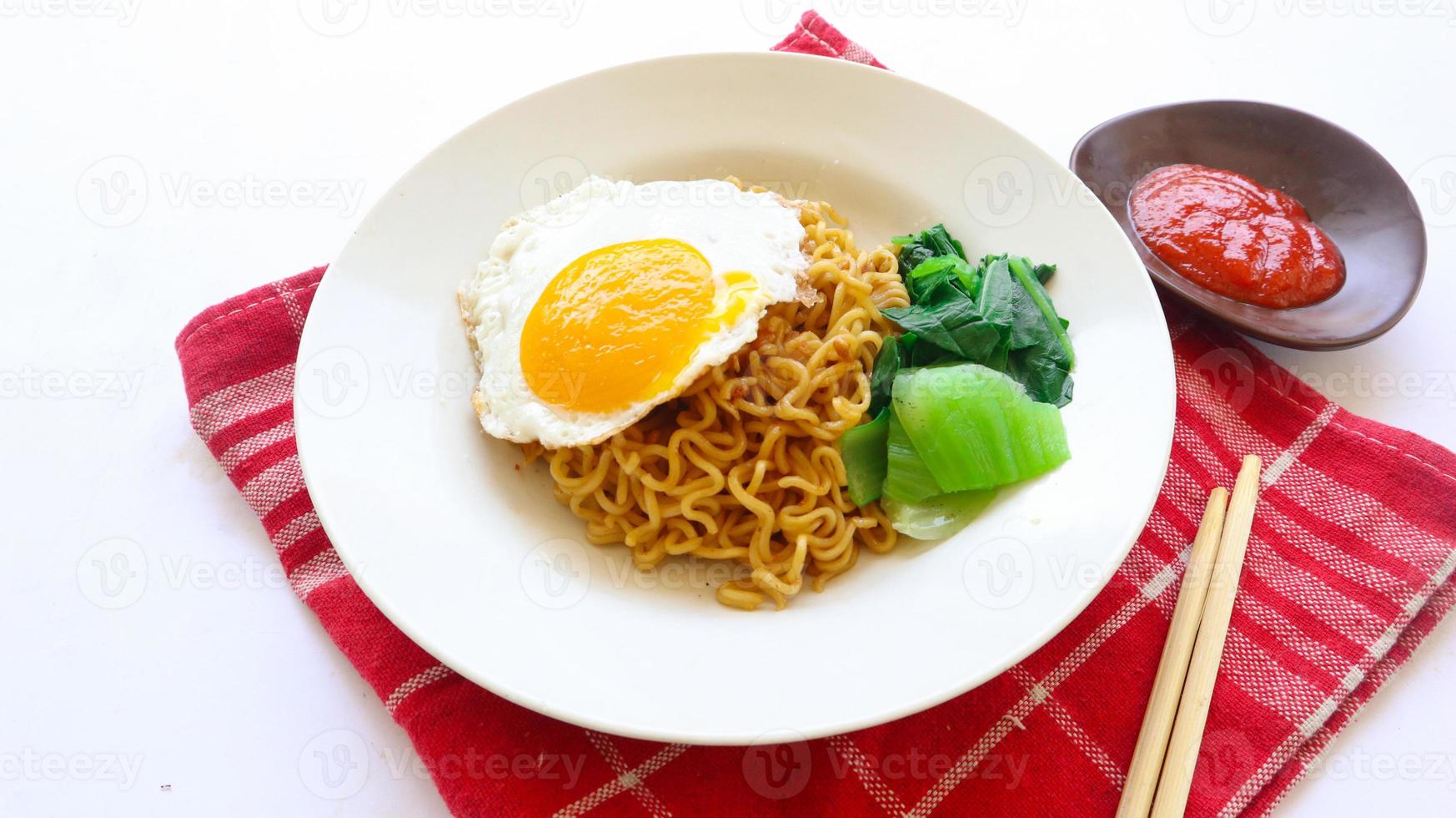 instant noodles served with egg fried and mustard greens on plate. instant fried noodle indomie photo