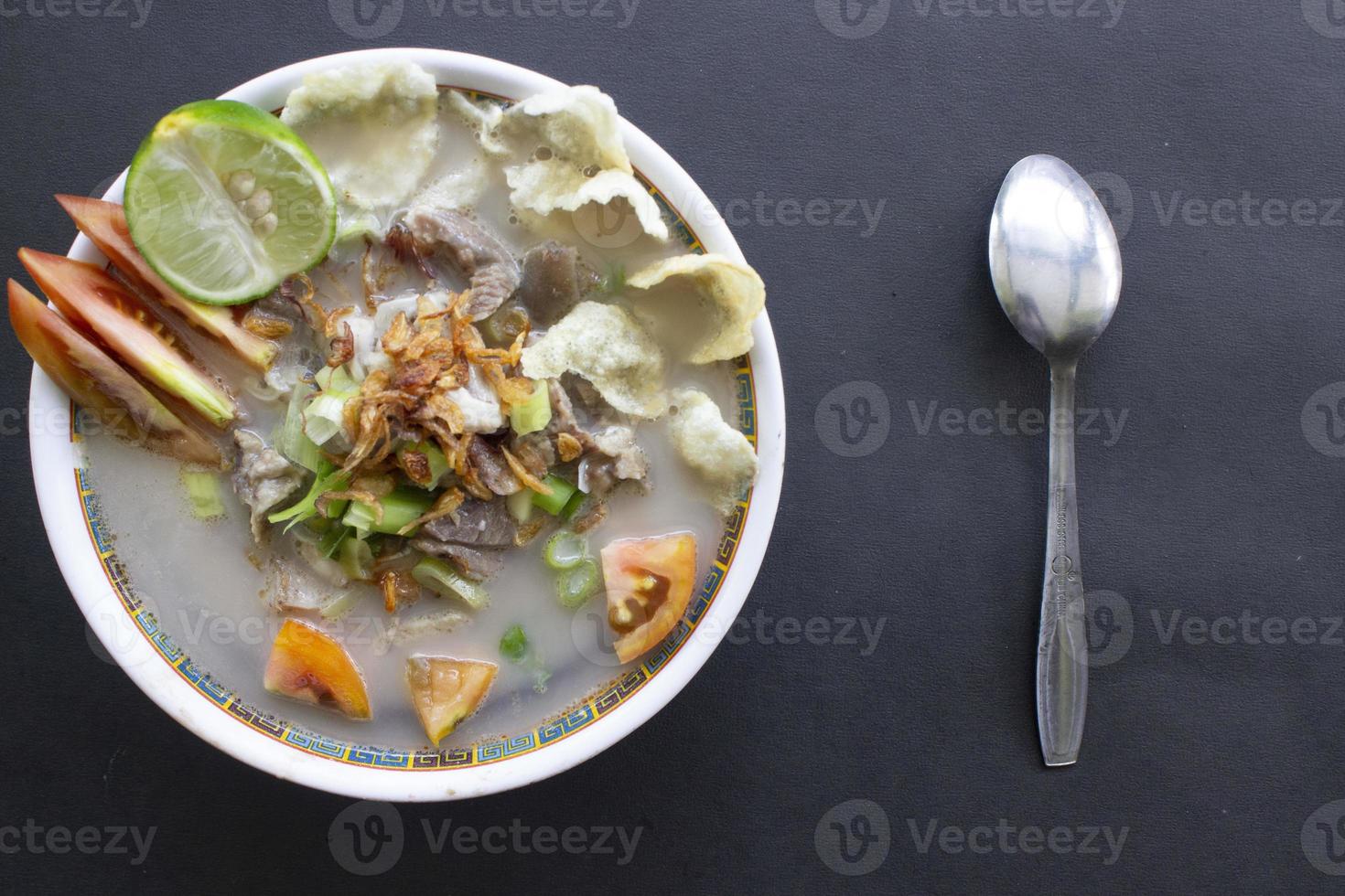 sop kaki kambing a traditional food from Betawi, Jakarta Indonesia, made from mutton or lamb, offal, spices. isolated on black background.This food is like lamb stew on black background photo