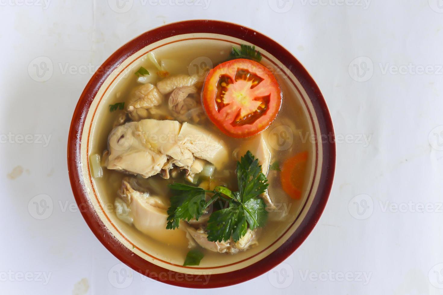 Chicken soup served with vegetables, tomatoes, celery in a bowl, spoon and fork. with black background photo