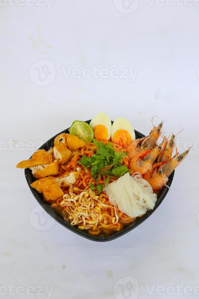 laksa, laksa curry made from vermicelli, noodles, bean sprouts, egg, tofu lime, and shrimp with a spicy soup sauce that is rich in spices. laksa served on bowl, isolated on white background. photo