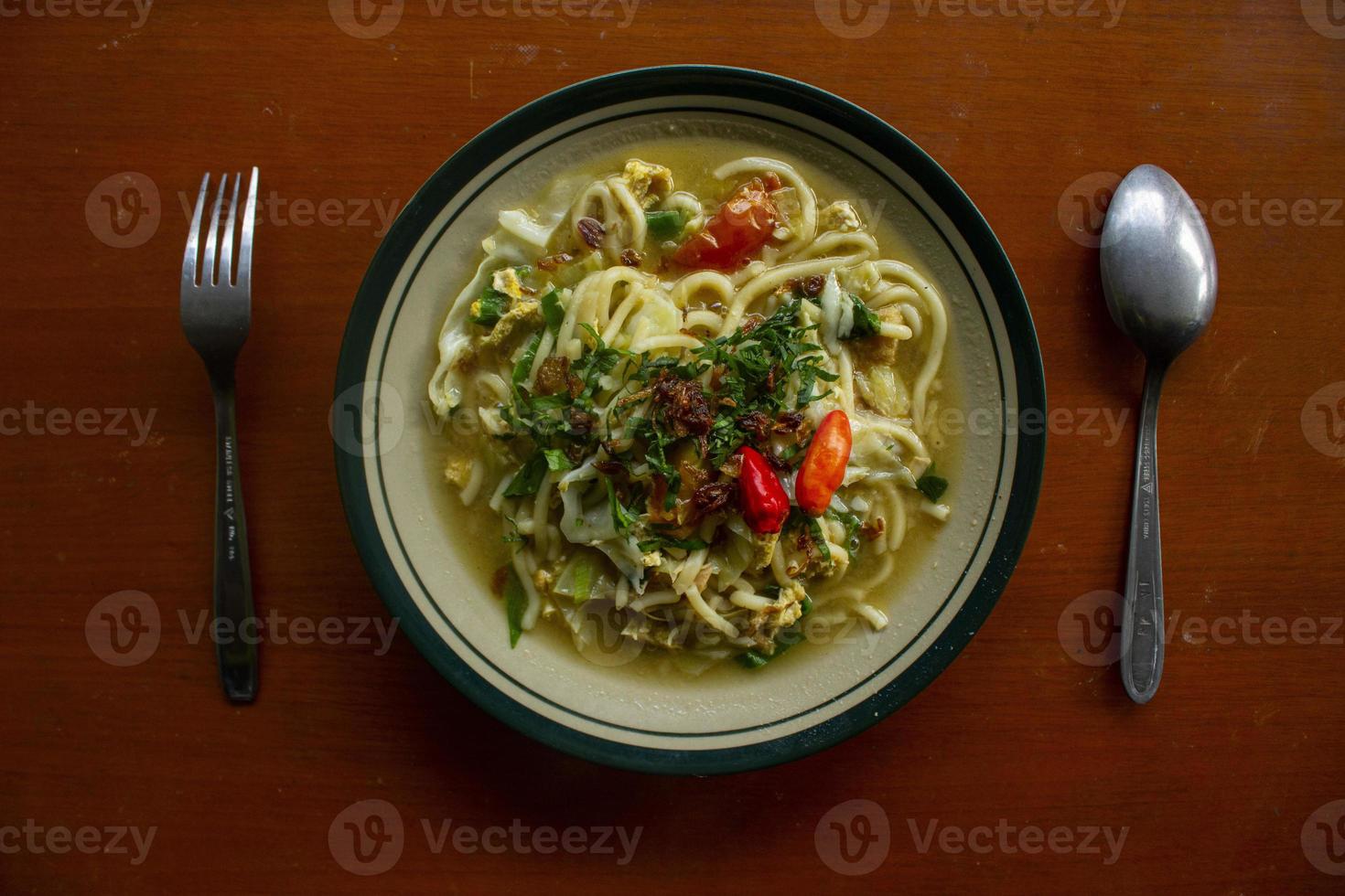 Mie godog Jawa or bakmi jawa or java noodle or Mie rebus or boiled noodles with spoon and fork. Indonesian traditional street food noodles from java, indonesia on white backgroud photo