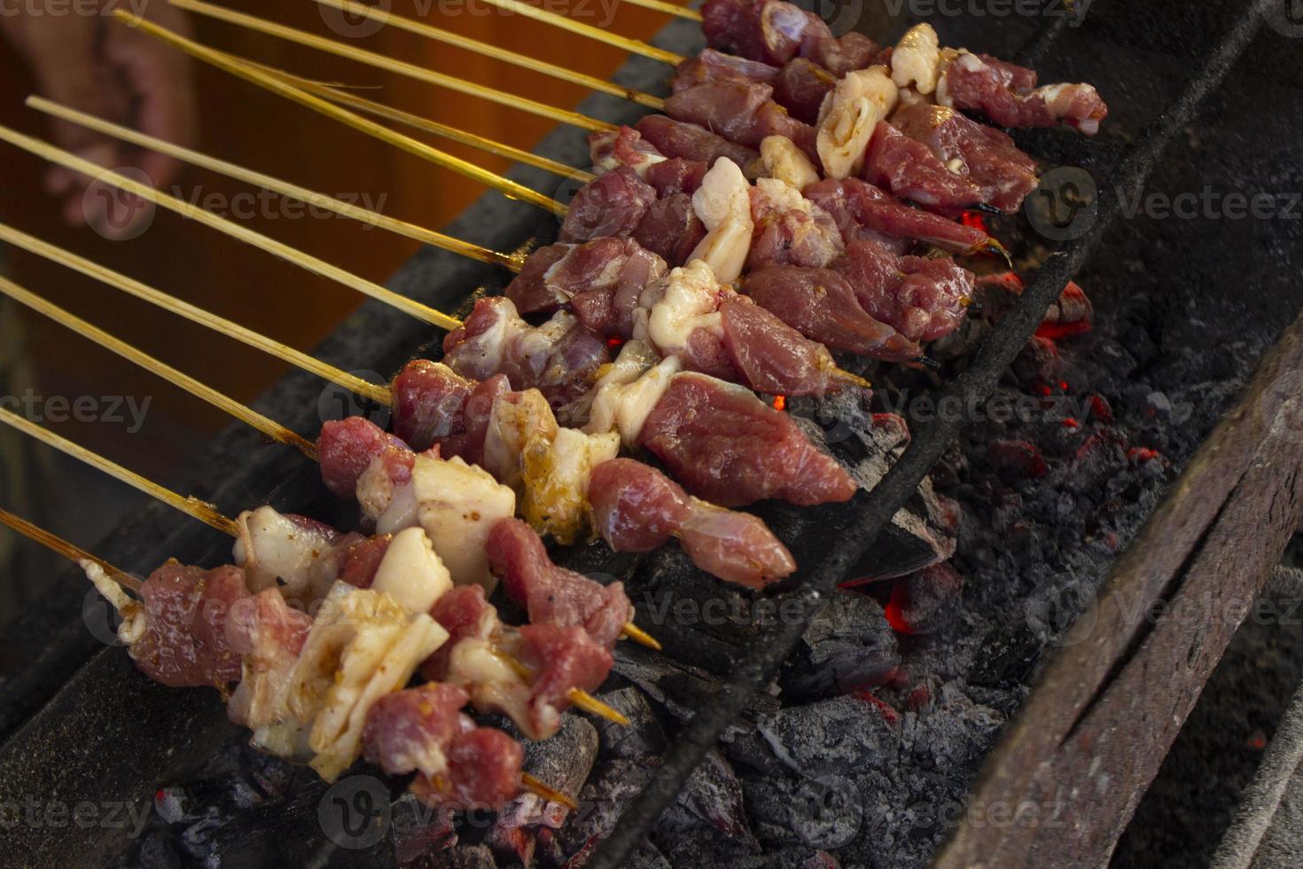 sate kambing o satay de cabra, cordero, cordero o carne de cabra satay con ingrediente de carbón en fuego rojo asado por personas. satay tradicional de yogyakarta, java, indonesia satay de cocina foto