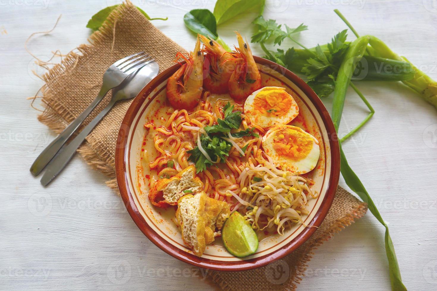 laksa, laksa curry made from vermicelli, noodles, bean sprouts, egg, tofu lime, and shrimp with a spicy soup sauce that is rich in spices. laksa served on bowl, isolated on white background. photo