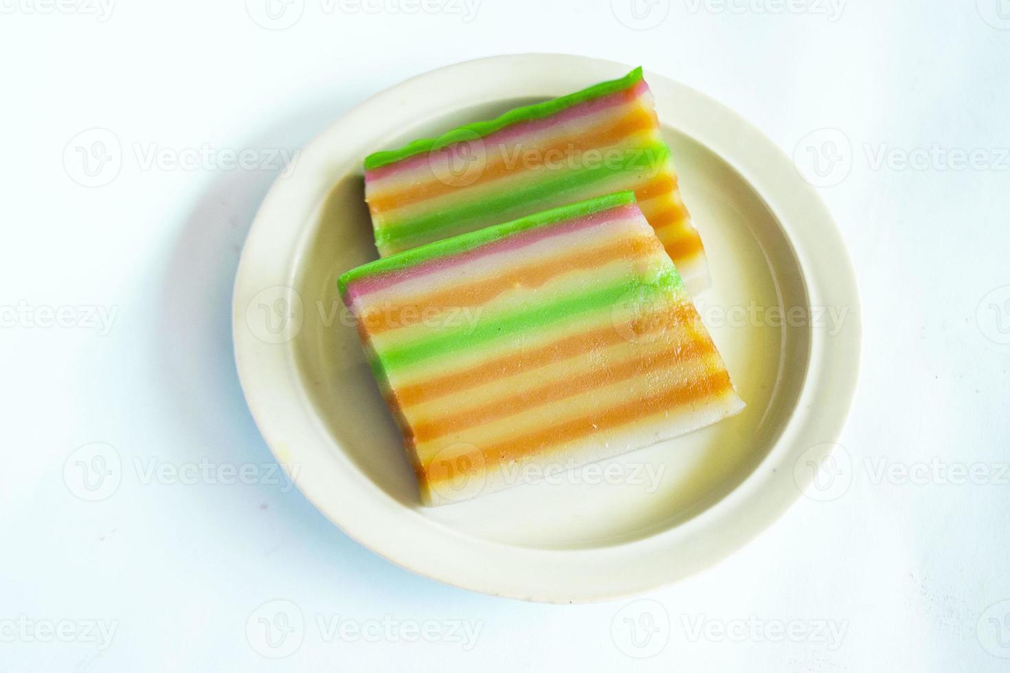 lapis cake or roti lapis or layer cake or lapis legit served in little plate isolated on white background made from rice flour, starch, coconut milk, sugar, salt and coloring photo