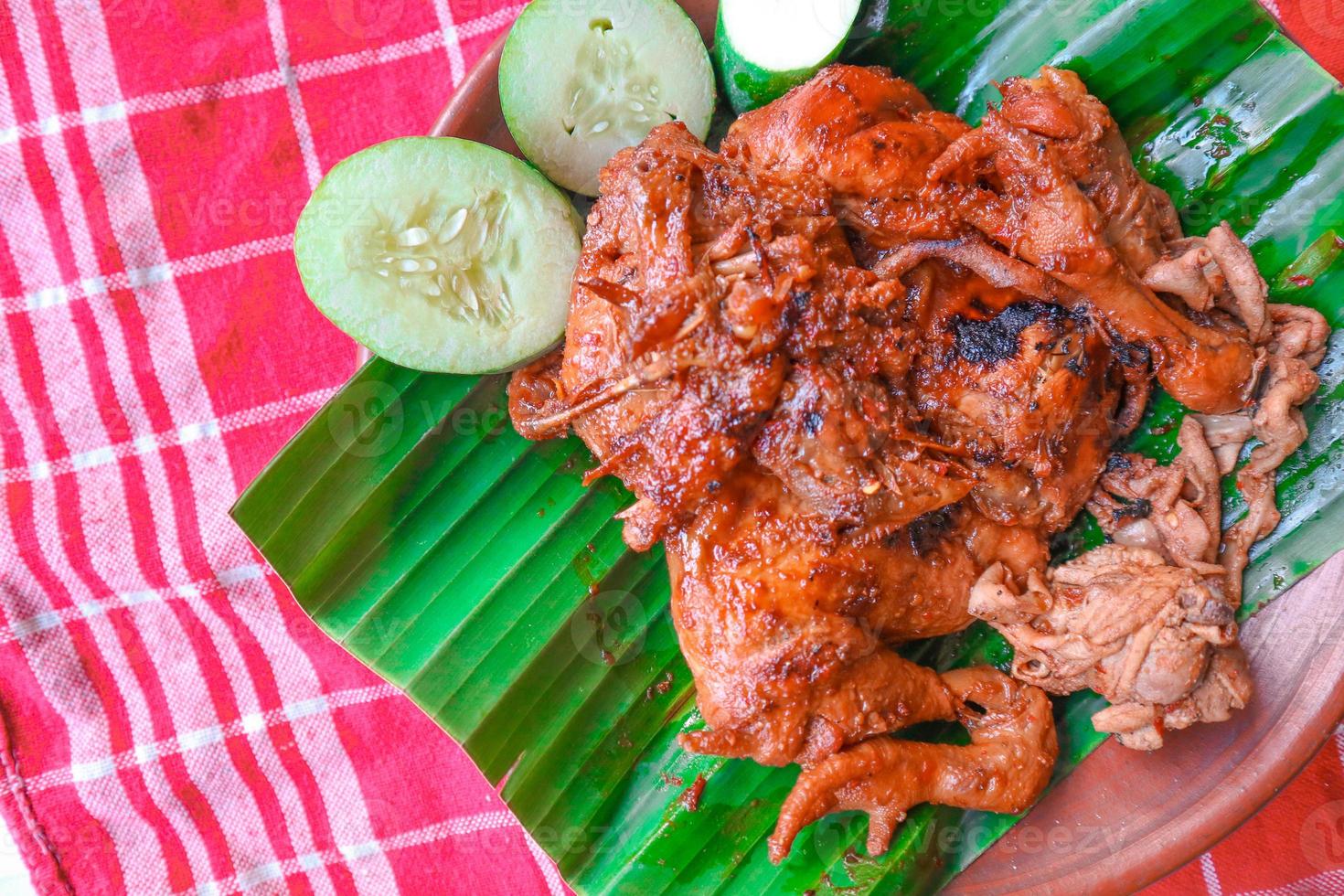 grilled chicken or ayam bakar with cucumber slash served on banana leaf and plate. ayam bakar is traditional grilled chicken from indonesia photo