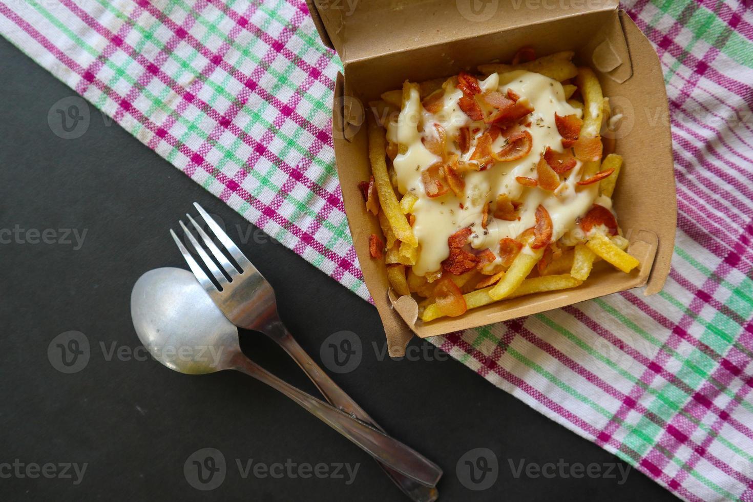 fried fries with with melted cheddar cheese or fried cheese with topping sausage slices on box photo