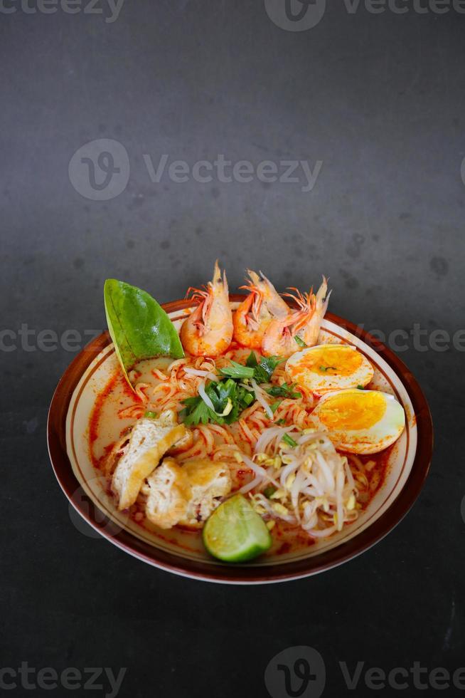 laksa, laksa curry made from vermicelli, noodles, bean sprouts, egg, tofu lime, and shrimp with a spicy soup sauce that is rich in spices. laksa served on bowl, isolated on white background. photo