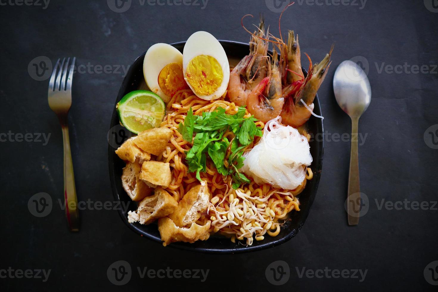 laksa, laksa curry made from vermicelli, noodles, bean sprouts, egg, tofu lime, and shrimp with a spicy soup sauce that is rich in spices. laksa served on bowl, isolated on white background. photo