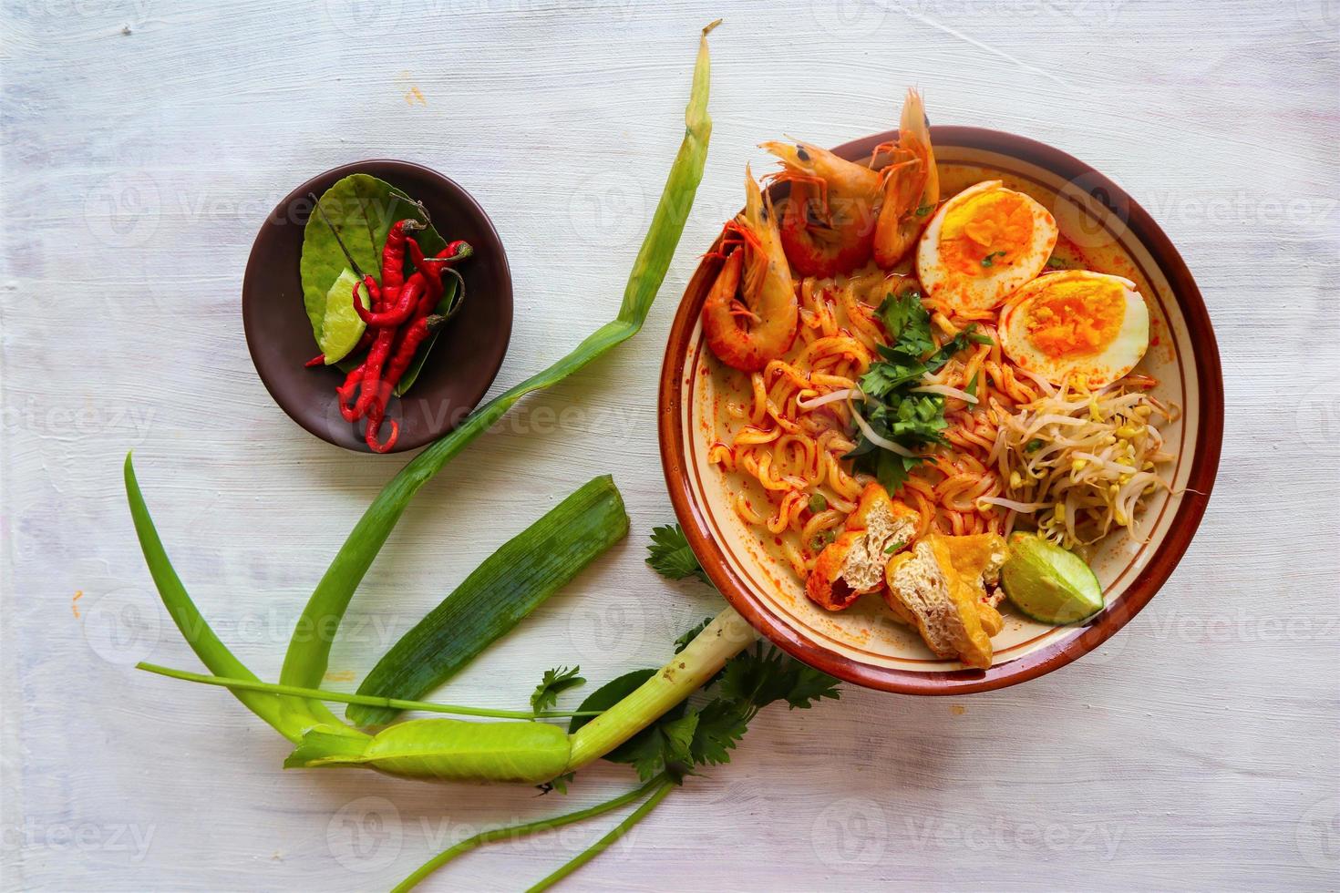 laksa, laksa curry made from vermicelli, noodles, bean sprouts, egg, tofu lime, and shrimp with a spicy soup sauce that is rich in spices. laksa served on bowl, isolated on white background. photo