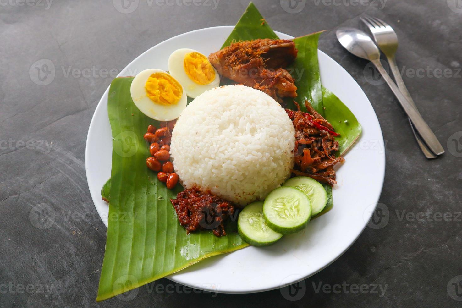 nasi lemak, is traditional malay made boiled eggs, beans, anchovies, chili sauce, cucumber. from dish served on a banana leaf photo