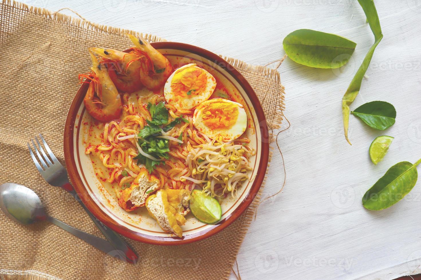 laksa, laksa curry made from vermicelli, noodles, bean sprouts, egg, tofu lime, and shrimp with a spicy soup sauce that is rich in spices. laksa served on bowl, isolated on white background. photo