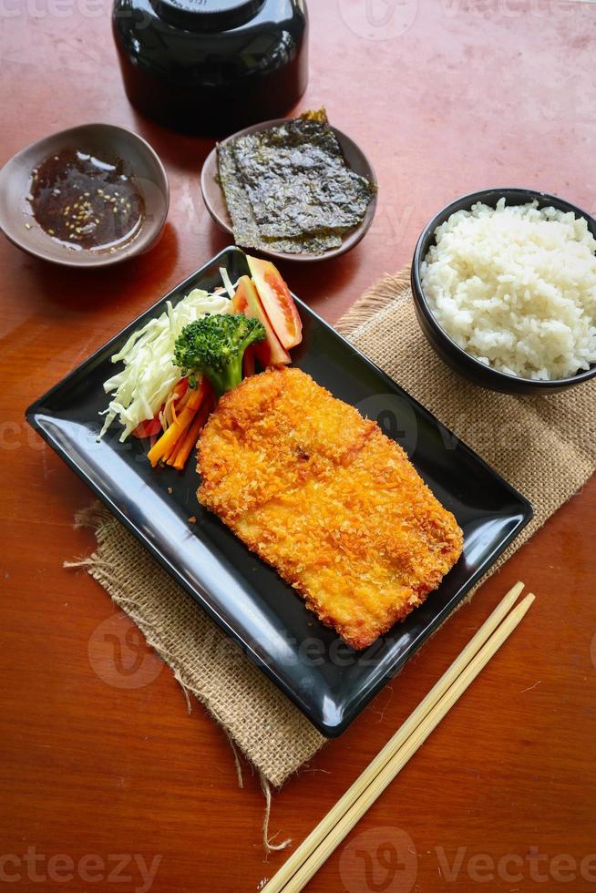 pollo katsu don es comida japonesa servida con salsa de soja en la mesa foto