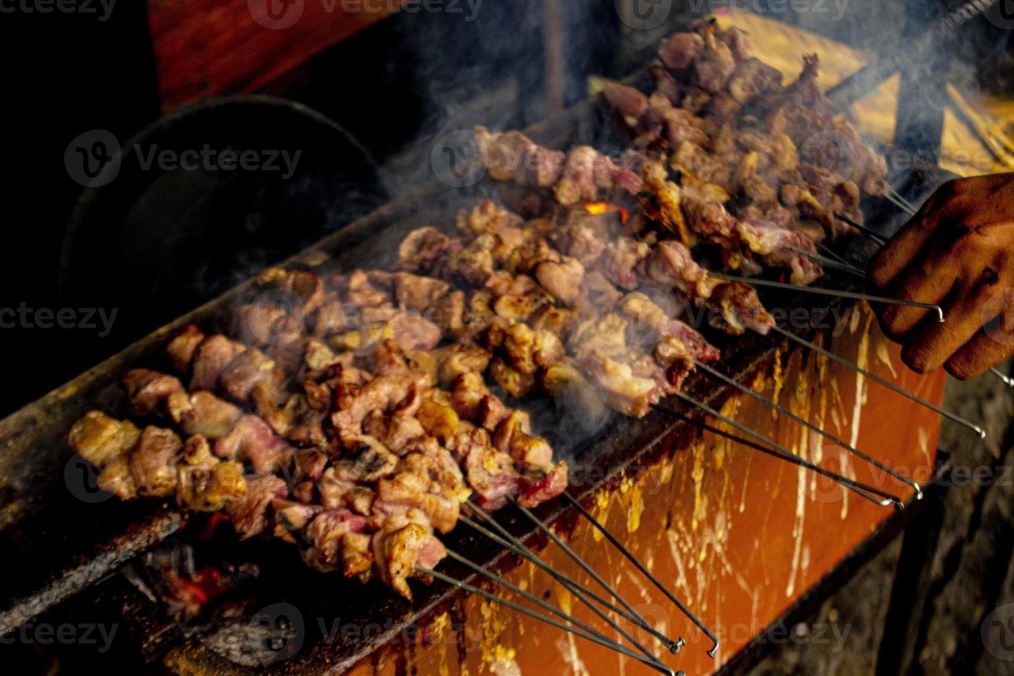 sate klatak o sate kambing o satay de cabra, cordero, cordero o carne de cabra satay con ingrediente de carbón en fuego rojo asado por personas, indonesia cocinando satay. con enfoque selectivo foto
