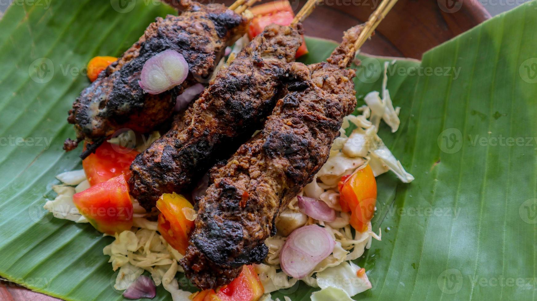 sate buntel or satay buntel is satay made from minced mutton wrapped in mutton fat and then grilled. seasoning with tomatoes, shallots, pepper, cabbage photo