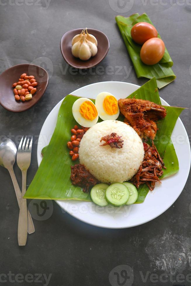 nasi lemak, is traditional malay made boiled eggs, beans, anchovies, chili sauce, cucumber. from dish served on a banana leaf photo