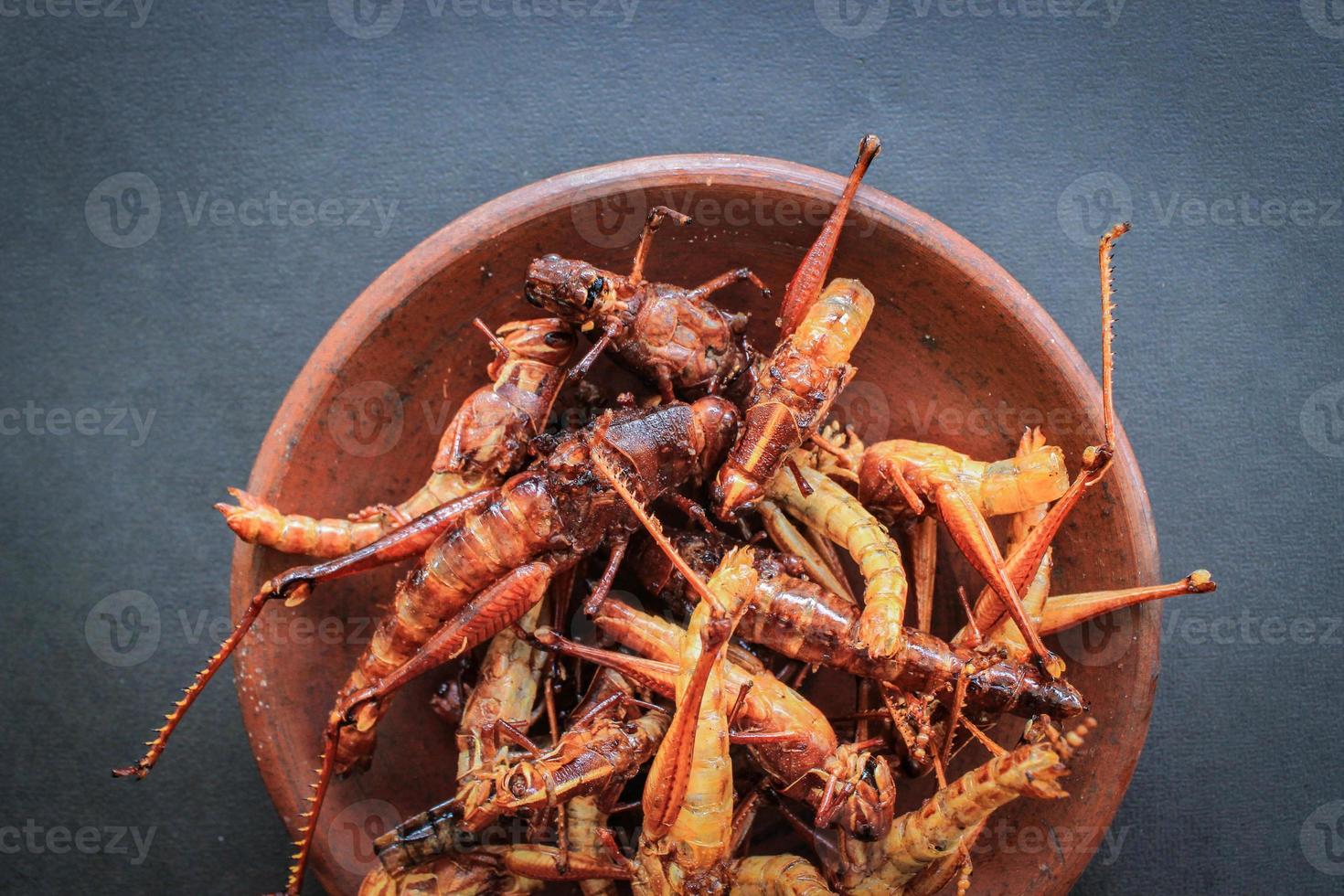 fried grasshopper or belalang goreng is traditional food from southeast asia, served with sambal, onion, garlic, chili on wood background photo