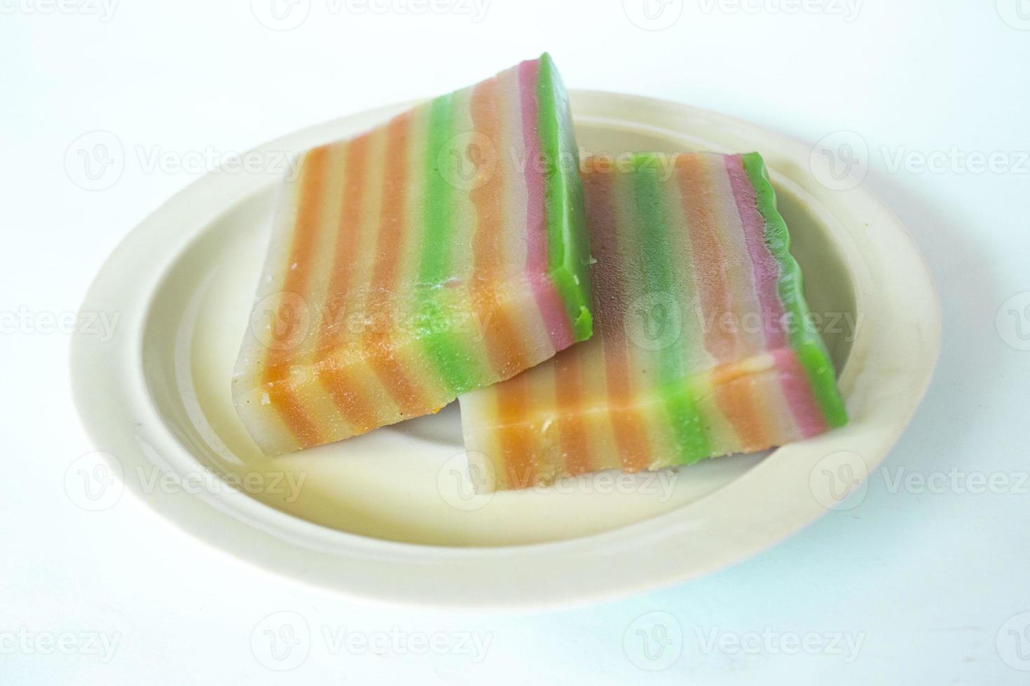 lapis cake or roti lapis or layer cake or lapis legit served in little plate isolated on white background made from rice flour, starch, coconut milk, sugar, salt and coloring photo