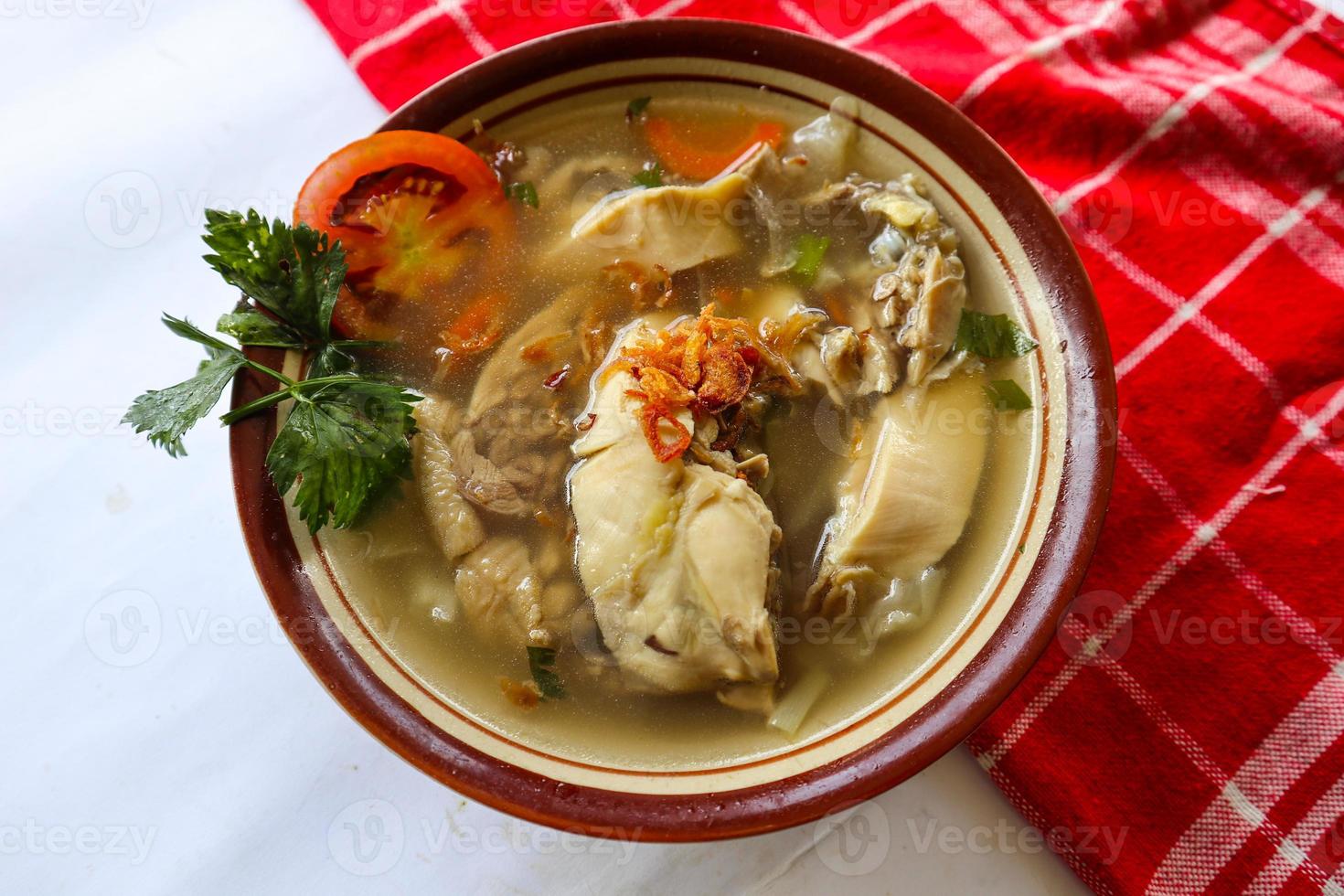 Chicken soup served with vegetables, tomatoes, celery in a bowl, spoon and fork. with black background photo