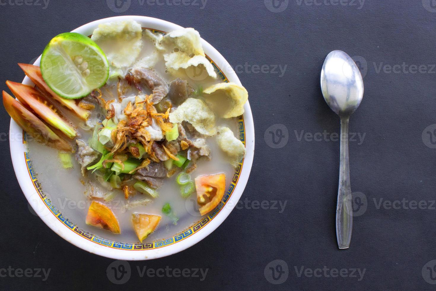 sop kaki kambing a traditional food from Betawi, Jakarta Indonesia, made from mutton or lamb, offal, spices. isolated on black background.This food is like lamb stew on black background photo