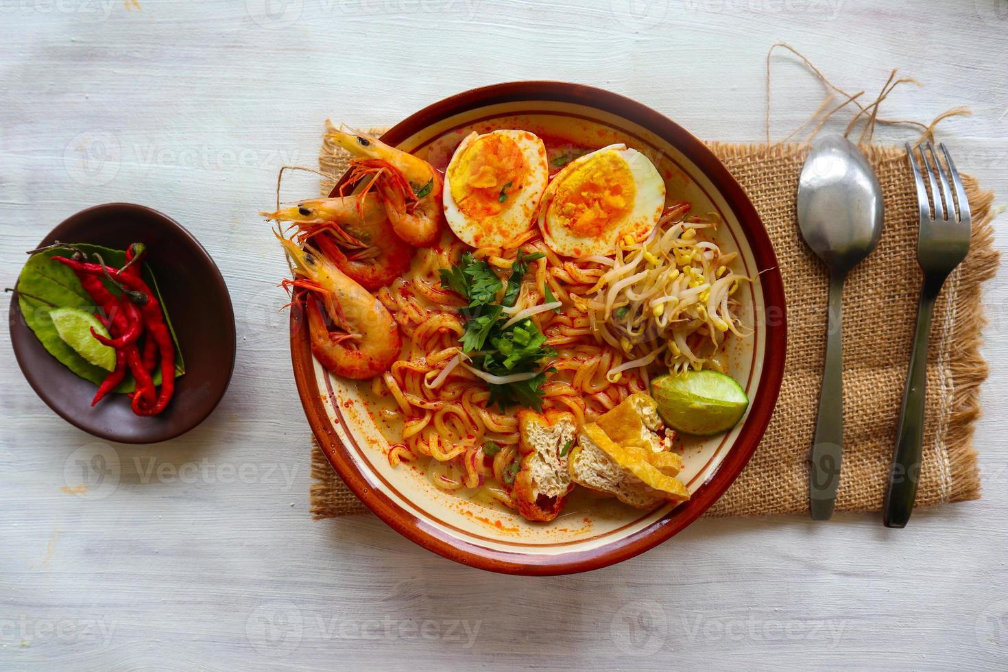 laksa, laksa curry made from vermicelli, noodles, bean sprouts, egg, tofu lime, and shrimp with a spicy soup sauce that is rich in spices. laksa served on bowl, isolated on white background. photo