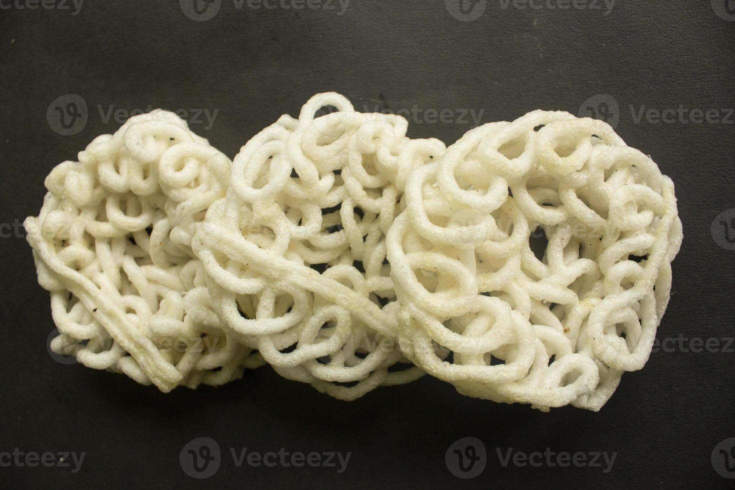 kerupuk or krupuk or crackers isolated on black background. kerupuk is snacks made from tapioca flour dough mixed with flavorings such as shrimp or fish. traditional snack from indonesia photo