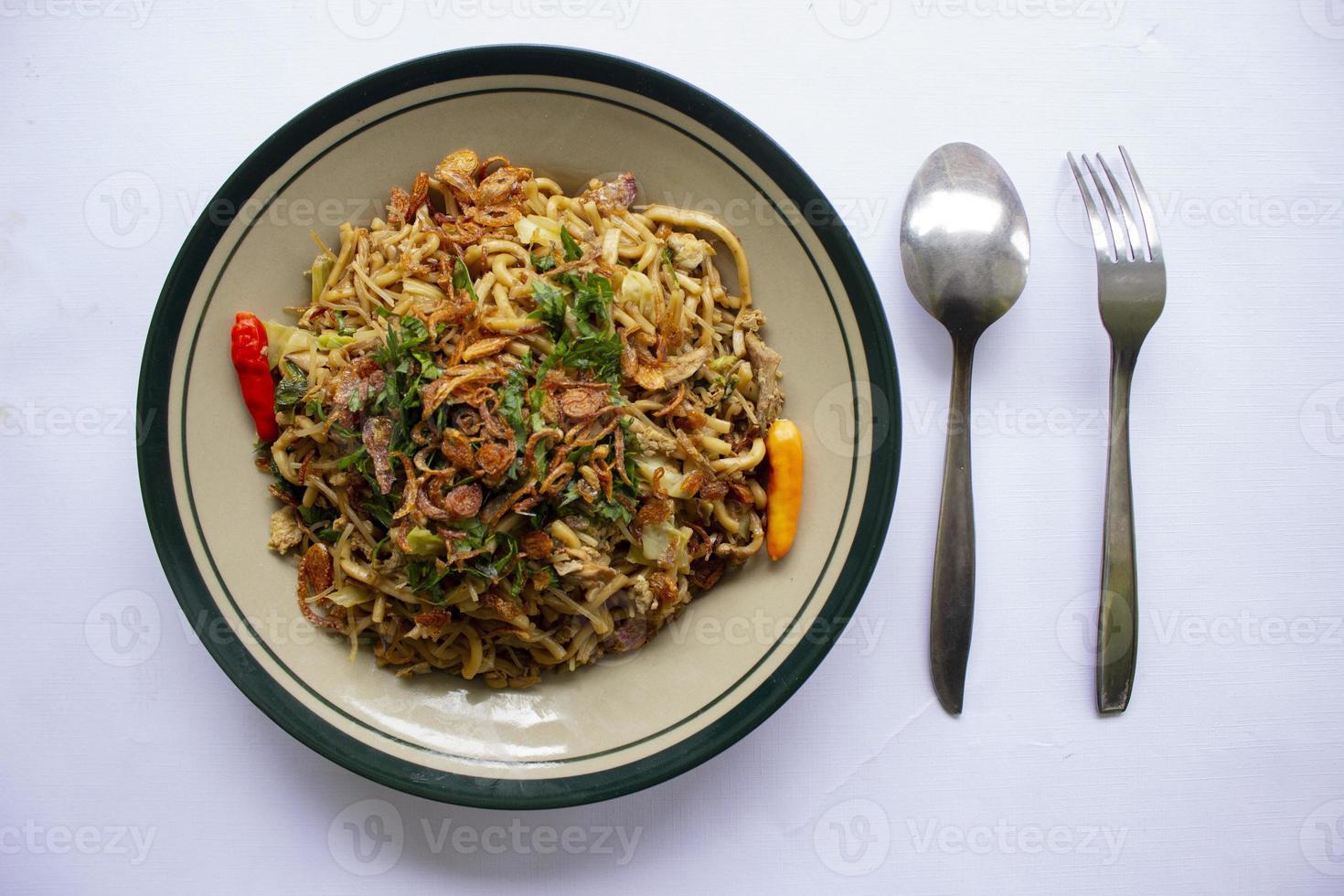 Mie Goreng Jawa or bakmi jawa or java noodle with spoon and fork. Indonesian traditional street food noodles from central java or Yogyakarta, indonesia on white background photo