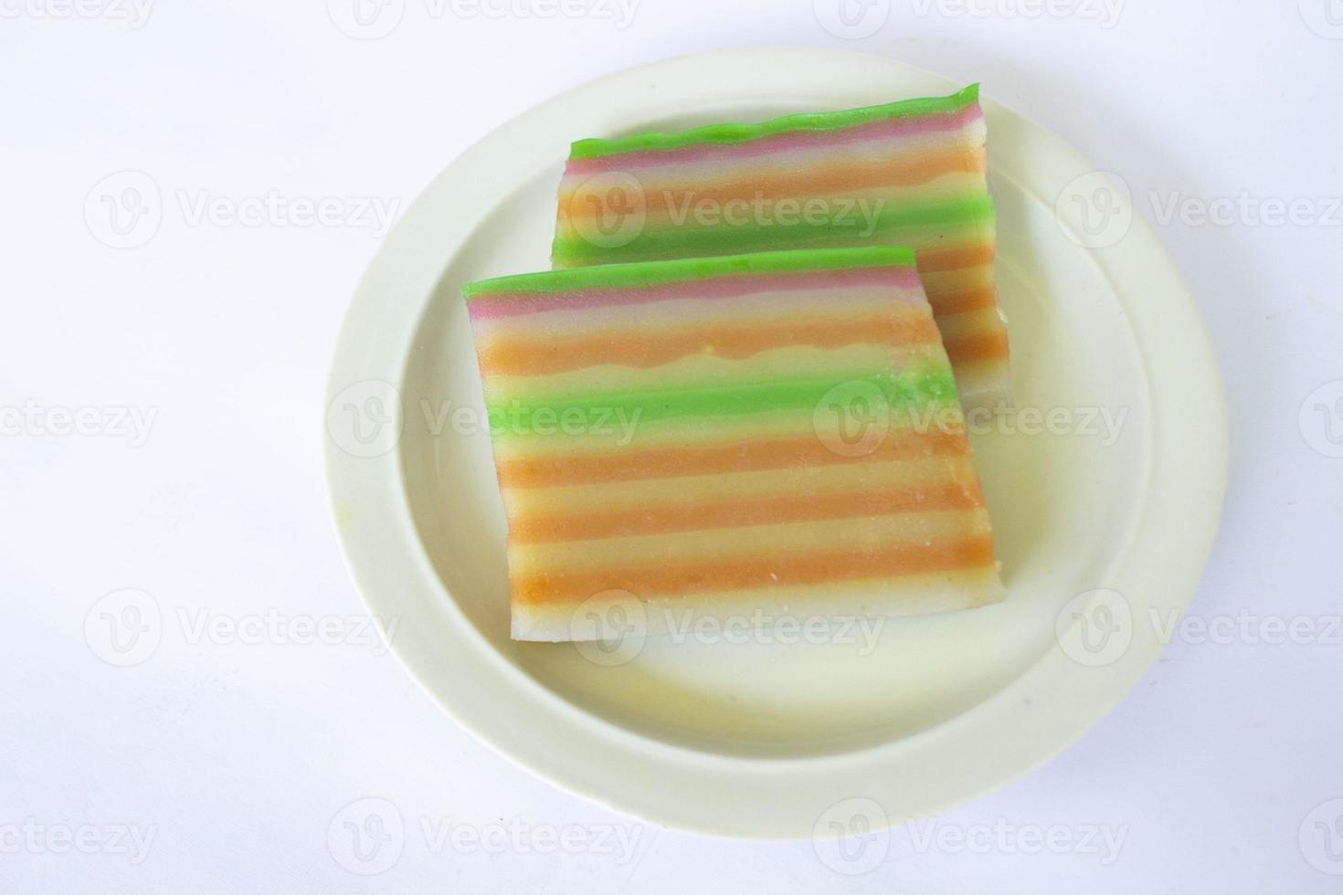 lapis cake or roti lapis or layer cake or lapis legit served in little plate isolated on white background made from rice flour, starch, coconut milk, sugar, salt and coloring photo