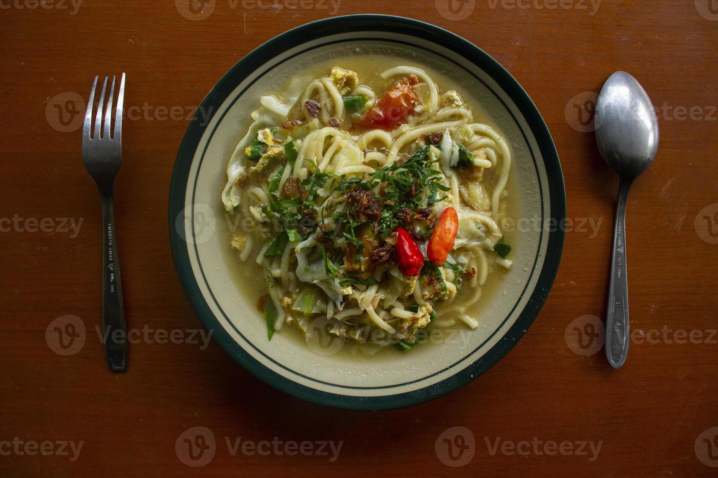 Mie godog Jawa or bakmi jawa or java noodle or Mie rebus or boiled noodles with spoon and fork. Indonesian traditional street food noodles from java, indonesia on white backgroud photo