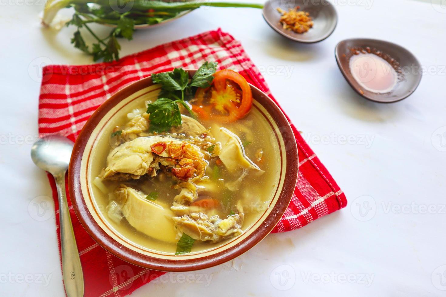 Chicken soup served with vegetables, tomatoes, celery in a bowl, spoon and fork. with black background photo