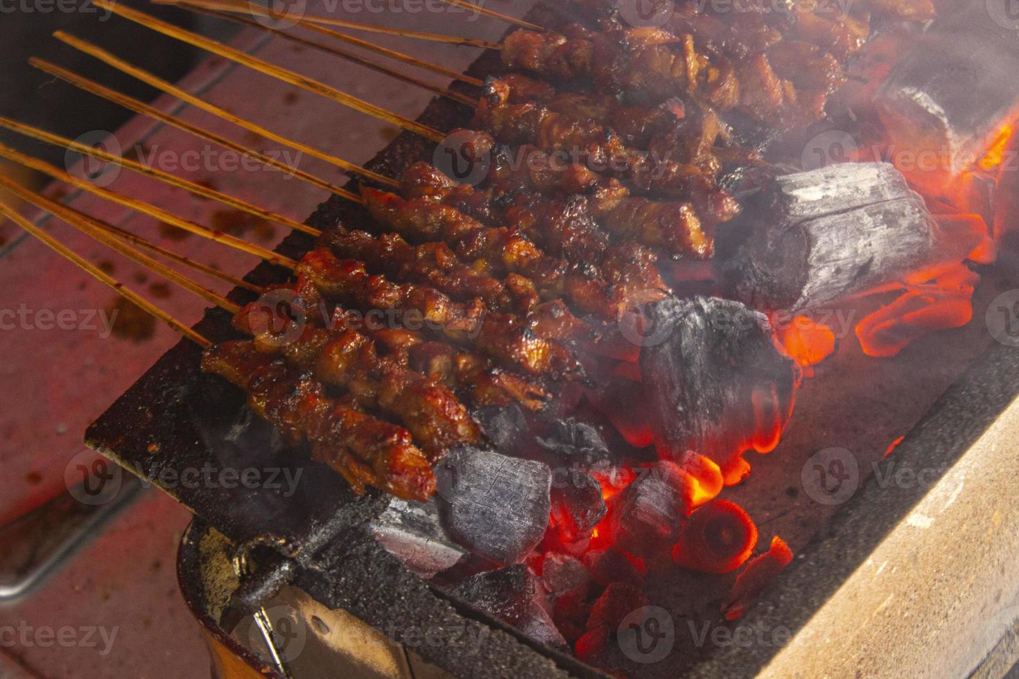 sate ayam or chicken satay with rice cake lontong served with peanut sauce, sliced chilis and shallot. photo with seletive focus