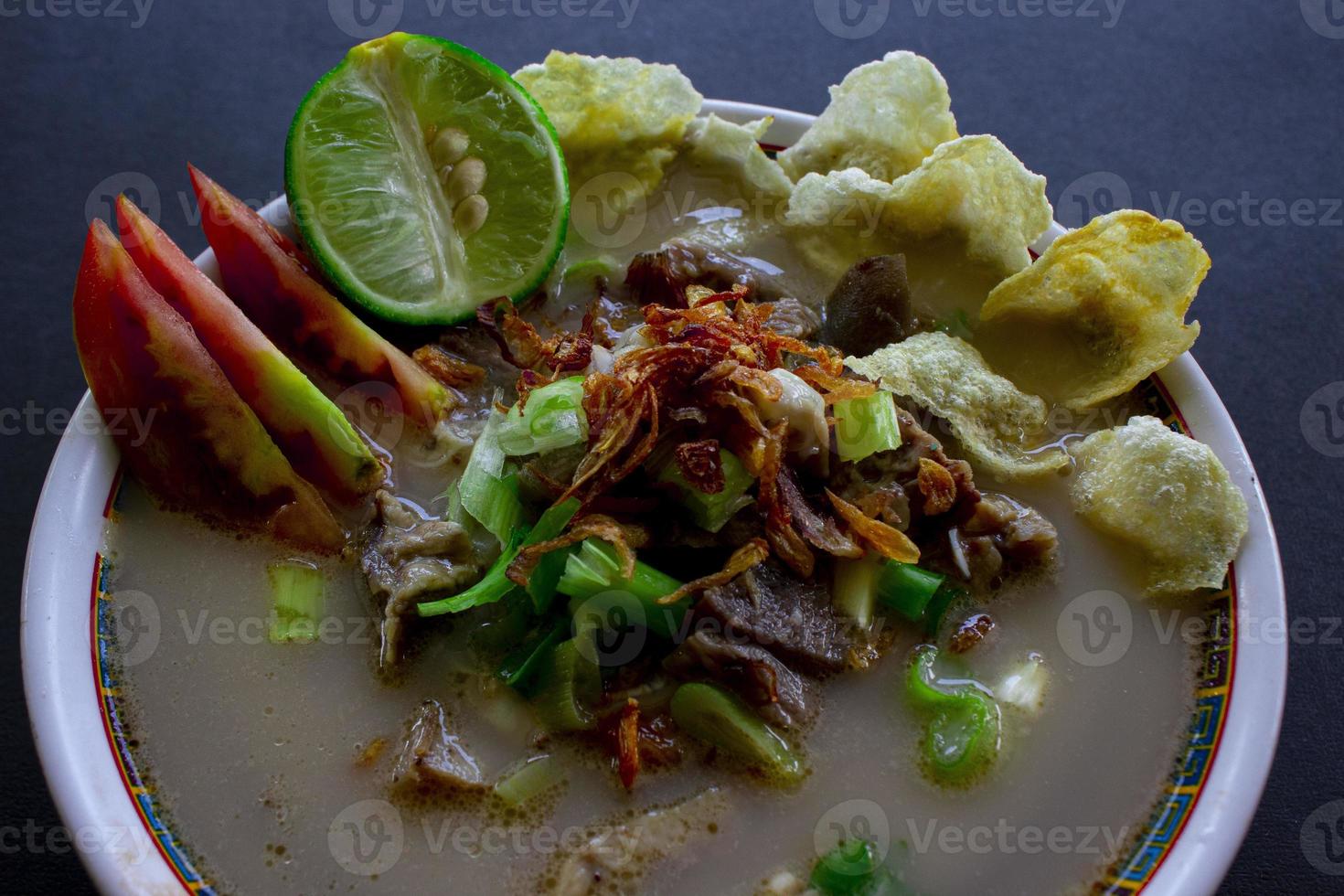 sop kaki kambing a traditional food from Betawi, Jakarta Indonesia, made from mutton or lamb, offal, spices. isolated on black background.This food is like lamb stew on black background photo