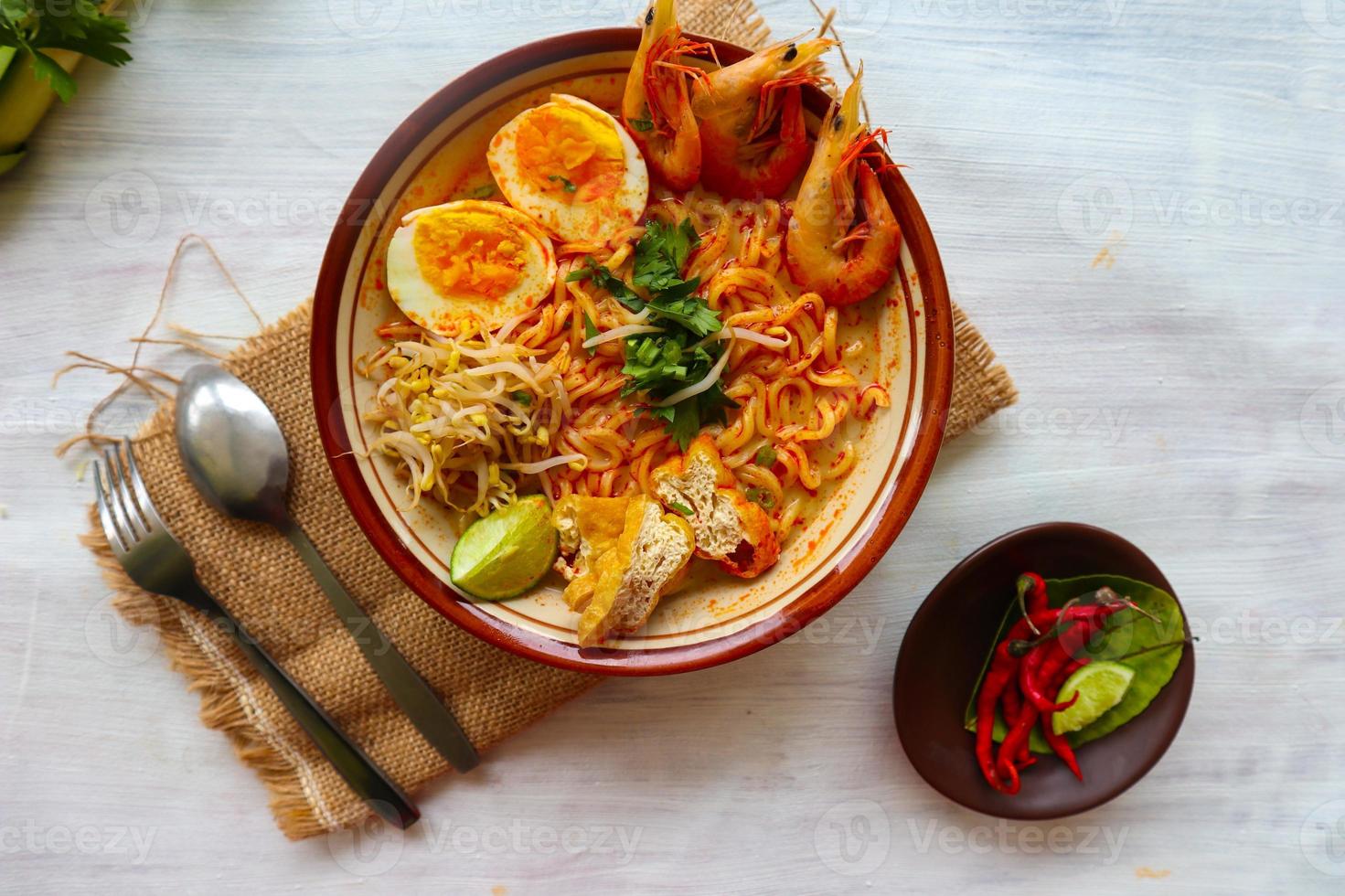 laksa, laksa curry made from vermicelli, noodles, bean sprouts, egg, tofu lime, and shrimp with a spicy soup sauce that is rich in spices. laksa served on bowl, isolated on white background. photo