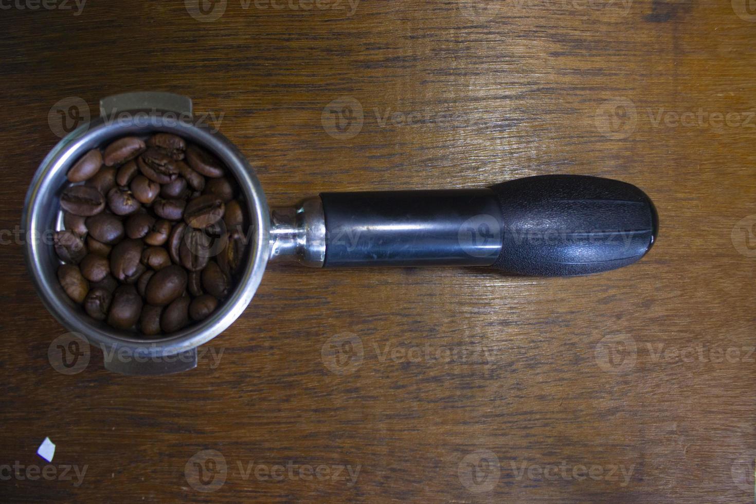 porta filter with ground coffee and coffee bean on table photo