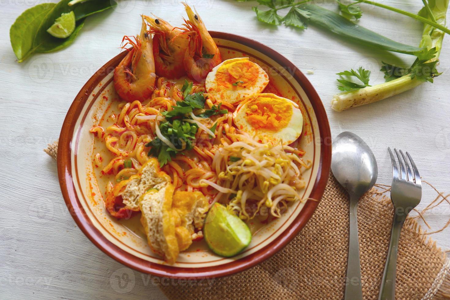 laksa, laksa curry made from vermicelli, noodles, bean sprouts, egg, tofu lime, and shrimp with a spicy soup sauce that is rich in spices. laksa served on bowl, isolated on white background. photo