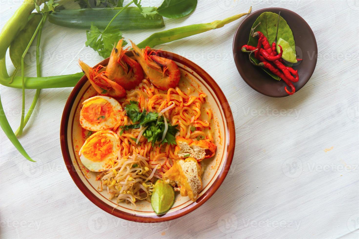 laksa, laksa curry made from vermicelli, noodles, bean sprouts, egg, tofu lime, and shrimp with a spicy soup sauce that is rich in spices. laksa served on bowl, isolated on white background. photo