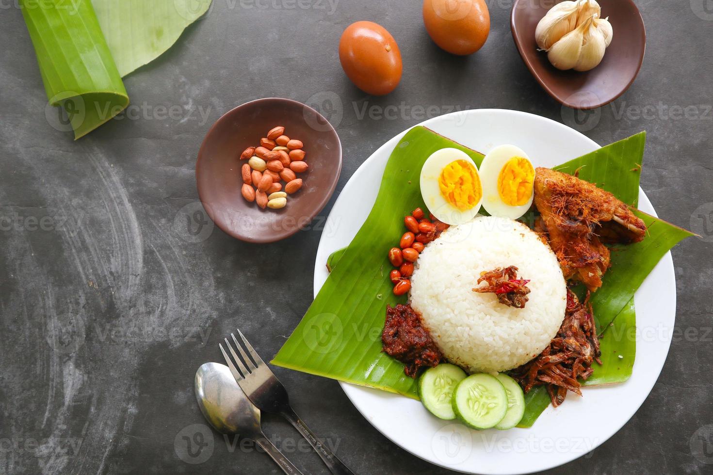 nasi lemak, is traditional malay made boiled eggs, beans, anchovies, chili sauce, cucumber. from dish served on a banana leaf photo