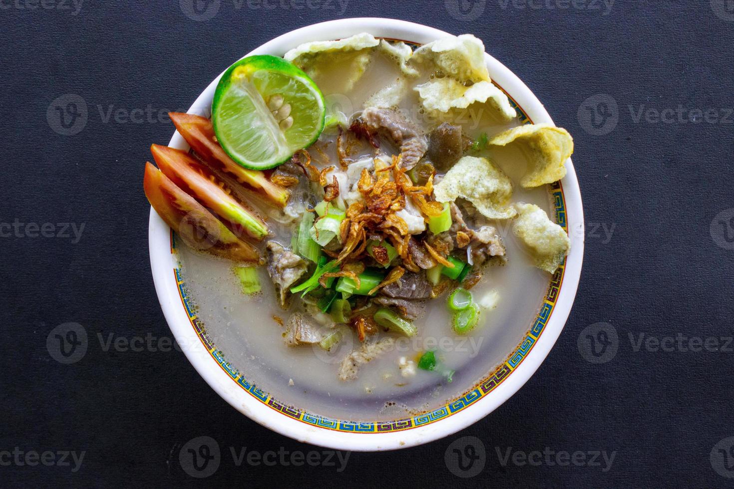 sop kaki kambing a traditional food from Betawi, Jakarta Indonesia, made from mutton or lamb, offal, spices. isolated on black background.This food is like lamb stew on black background photo