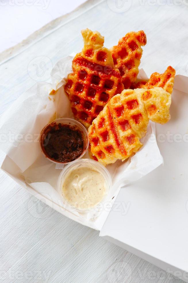 gofre croissant o croffle con salsa de chocolate servido en caja y fondo blanco foto