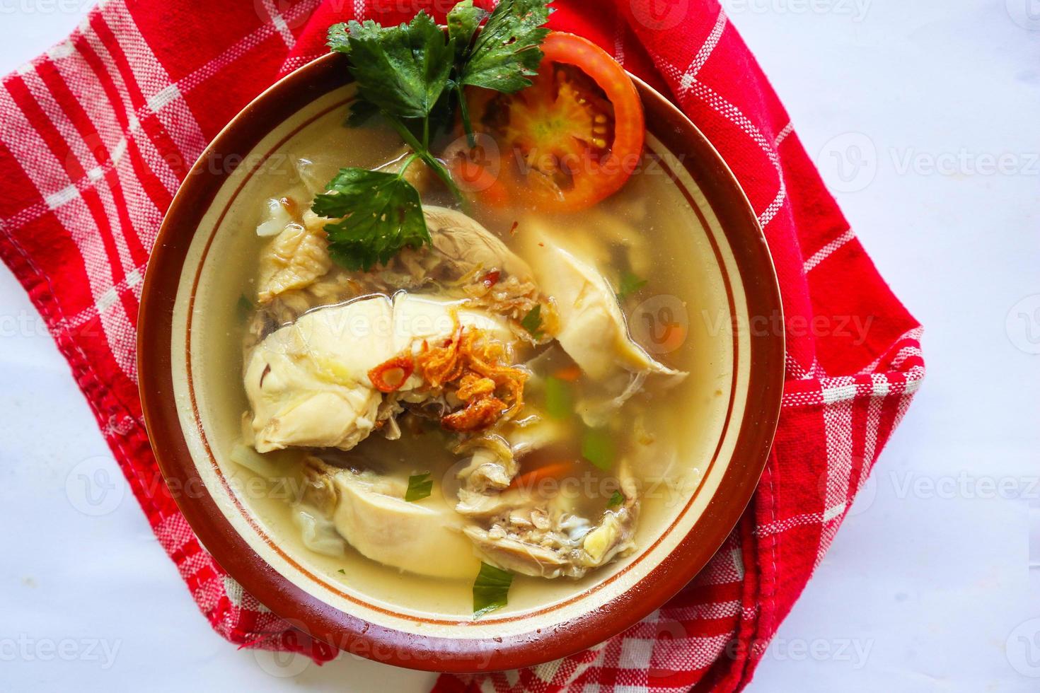 Chicken soup served with vegetables, tomatoes, celery in a bowl, spoon and fork. with black background photo