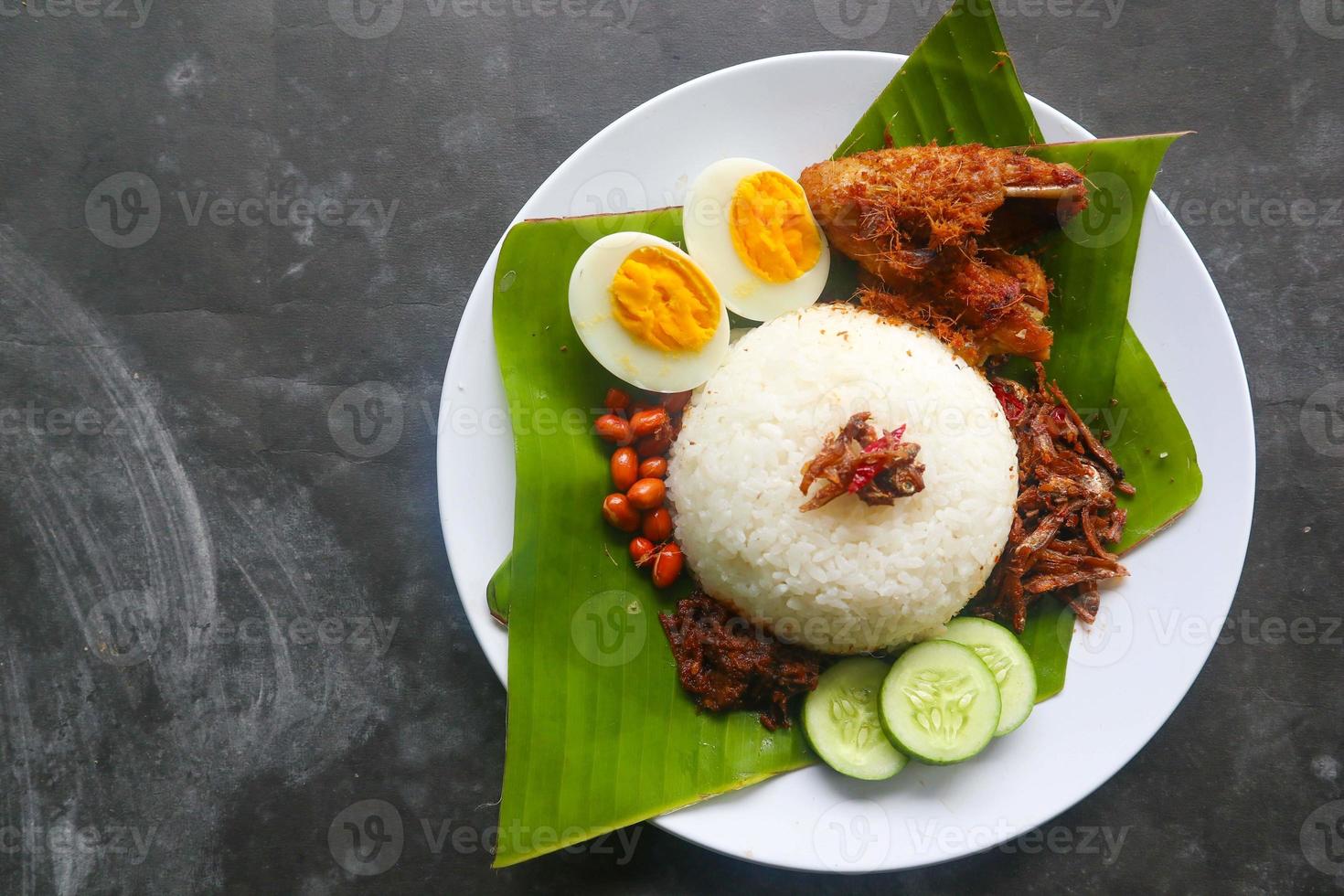 nasi lemak, is traditional malay made boiled eggs, beans, anchovies, chili sauce, cucumber. from dish served on a banana leaf photo