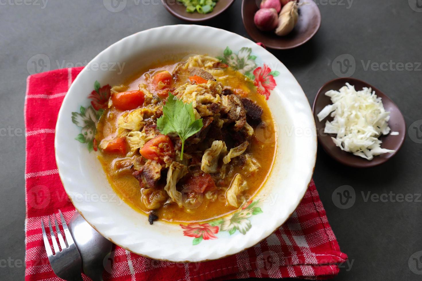 Goat Curry or gulai kambing, food from asia. Delicious goat meat curry served in a bowl.served with tomato, seasoning, celery and cabbage photo